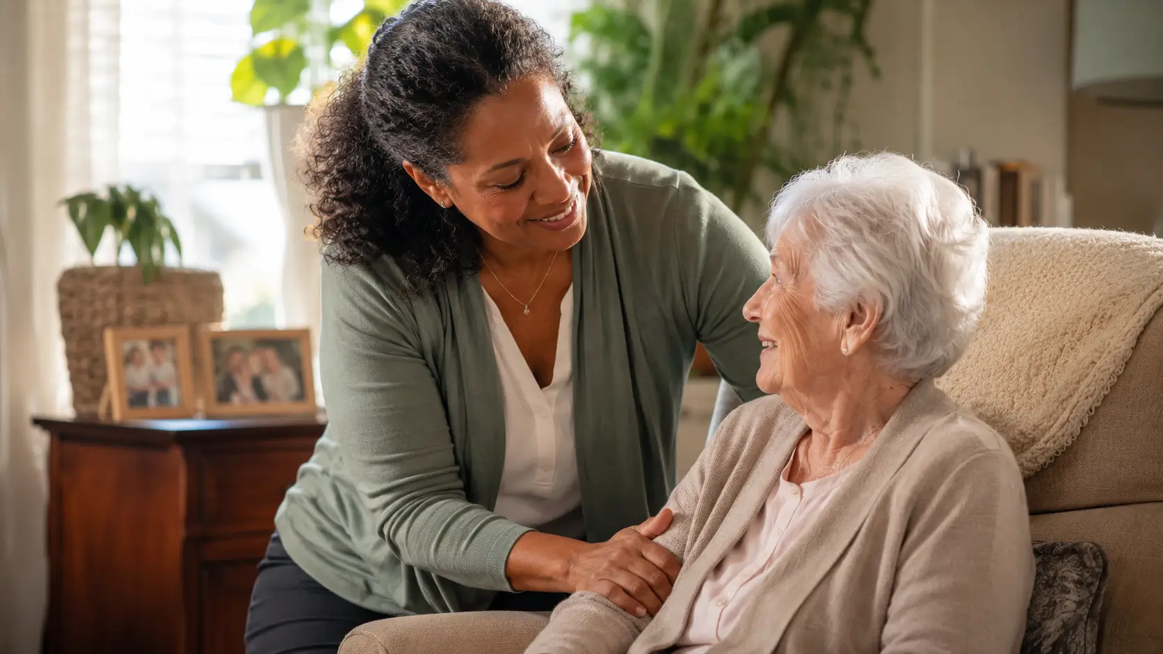 Compassionate caregiver attending to a smiling elderly woman in her living room at home